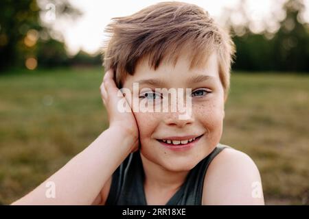 Ritratto di Happy Boy con lentiggini appoggiati al gomito Foto Stock