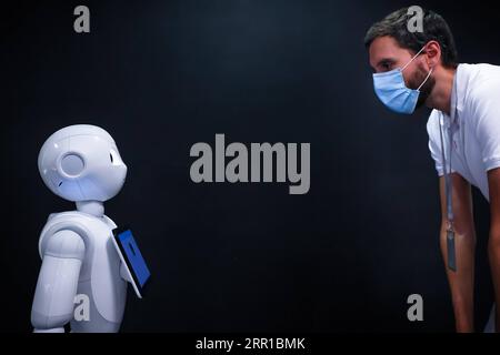 200912 -- PECHINO, 12 settembre 2020 -- Un uomo che indossa una maschera guarda un robot Pepper alla SoftBank Robotics di Parigi, in Francia, 10 settembre 2020. Con una nuova funzione, il robot Pepper è in grado di rilevare se le persone indossano maschere facciali e, in caso contrario, di indicarle di indossarle. Foto di /Xinhua XINHUA FOTO DEL GIORNO AurelienxMorissard PUBLICATIONxNOTxINxCHN Foto Stock