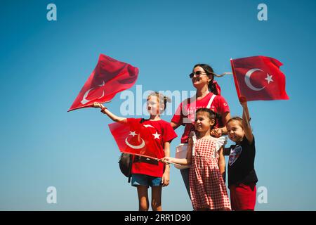 Smirne, Turchia - 30 agosto 2023: Durante il giorno della Vittoria a Cumhuriyet Square, una madre e tre figlie in abiti a tema rosso e bandiera sventolano fla turca Foto Stock