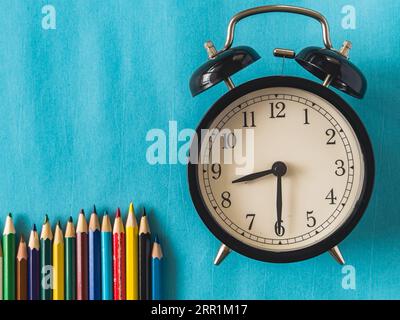 spazio di copia per la registrazione del display del prodotto. Primo piano di una classica sveglia su sfondo blu con le matite. Foto di alta qualità Foto Stock