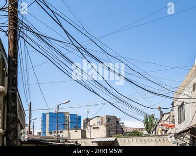 Cavi e fili elettrici sopra le case nel centro della città di Erevan nelle soleggiate giornate estive Foto Stock