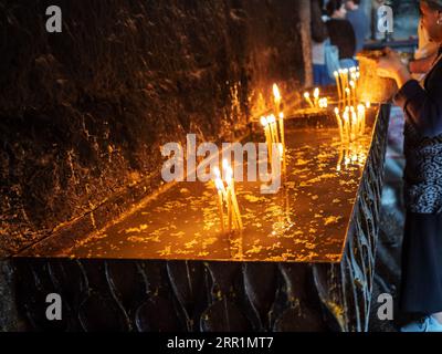 Sevan, Armenia - 25 agosto 2023: Le candele funebri bruciano nella chiesa di Surp Arakelots nel monastero di Sevanavank. Il monastero di Sevan fu fondato nel 874 Foto Stock