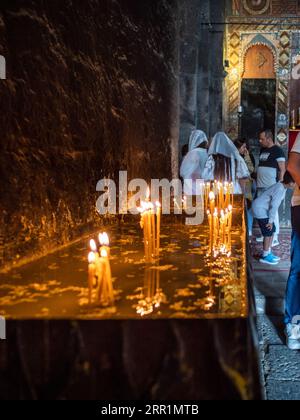 Sevan, Armenia - 25 agosto 2023: Candele bruciate nella chiesa di Surp Arakelots nel monastero di Sevanavank. Il monastero di Sevan fu fondato nel 874 Foto Stock