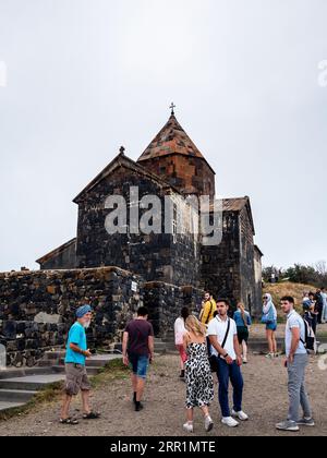 Sevan, Armenia - 25 agosto 2023: Turisti vicino alla chiesa Surp Arakelots del monastero di Sevanavank il giorno estivo. Il monastero di Sevan fu fondato nell'8 Foto Stock