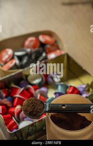 Natura morta con un contenitore pieno di caffè macinato e una lattina con capsule di vari tipi di caffè Foto Stock