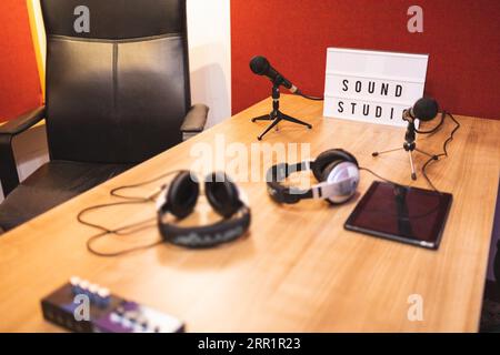 Camera decorata e illuminata con sedia vuota e tavolo con insegne sonore, microfoni per tablet su treppiedi, cuffie per tablet e amplificatore Foto Stock