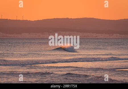 Vista mozzafiato del vibrante cielo al tramonto sul mare ondulato in serata Foto Stock