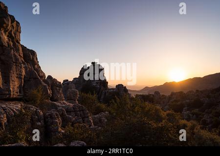 Splendida vista sul pendio montano della Sierra del Torcal con prati verdi e alte cime situate contro il cielo azzurro a Malaga al tramonto Foto Stock