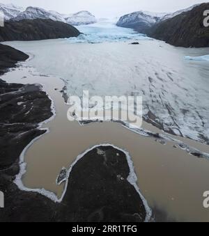 Vista aerea dell'acqua bruna del lago ghiacciata con crepe di ghiaccio tra le montagne innevate dell'isola di Madeira in Portogallo sotto il cielo blu sfocato e senza nuvole a da Foto Stock