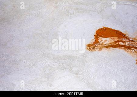Superficie in marmo testurizzato di pietra bianca con linee disomogenee e macchie arancioni Foto Stock