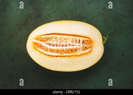 Melone ovale grande, tagliare metà con semi su sfondo rustico verde, vista dall'alto Foto Stock