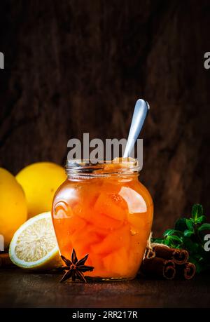 Marmellata di quince autunnale o confiture in vaso di vetro con cannella, succo di limone e anice su fondo rustico di legno Foto Stock