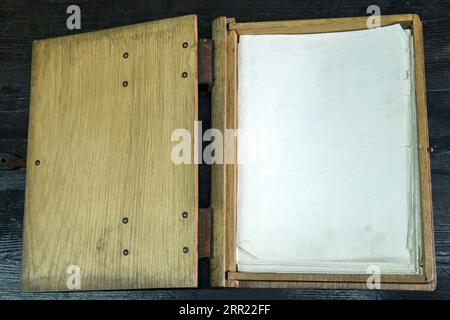 vecchio registro in una cassa di legno con chiusure su un piano nero, aperto Foto Stock
