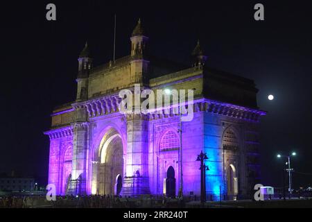 Luci colorate illuminano la porta d'India a Mumbai, un monumento ad arco eretto nel 1911 per commemorare lo sbarco di re Giorgio V, il primo monarca britannico a visitare l'India Foto Stock