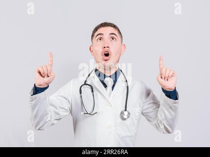 Un dottore stupito che indica una promozione. Medico maschile che guarda e indica un medico isolato, sorpreso che indichi un annuncio Foto Stock