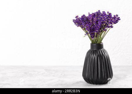 Bouquet di lavanda in moderno vaso in ceramica nera su sfondo grigio pietra copia spazio Foto Stock