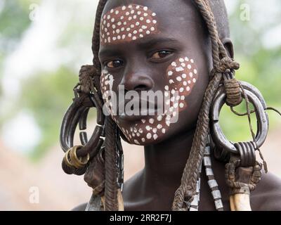 Ragazza della tribù dei Mursi con copricapo e face painting, ritratto, Etiopia Foto Stock