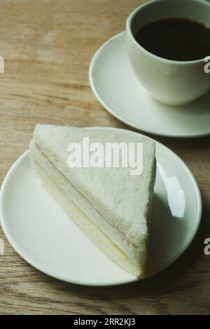 sandwich al formaggio con prosciutto sul piatto e tazza di caffè nero Foto Stock