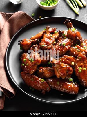 Ali di pollo dolci e piccanti sul piatto su fondo di pietra scura. Vista ravvicinata Foto Stock