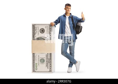 Studente maschio appoggiato su una pila di banconote da dollari e con pollice che si muove isolato su sfondo bianco Foto Stock