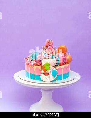 Torta di compleanno per il compleanno dei gemelli di 5 anni. Torta di colore blu e rosa, biscotto di pan di zenzero a forma di numero 5, sfondo semplice Foto Stock