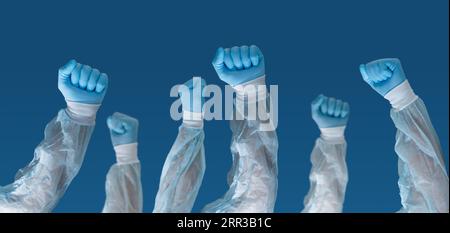 Ritratto del personale medico che indossa maschere facciali con le mani in alto e tenendo in mano un cartello che dice "personale sanitario". concetto di pandemia e crisi sanitaria. Foto Stock