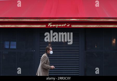 201030 -- PARIGI, 30 ottobre 2020 -- Un uomo cammina davanti al ristorante chiuso Fouquet S presso gli Champs-Elysees Avenue a Parigi, Francia, 30 ottobre 2020. La Francia ha registrato 47.637 casi di infezione da coronavirus nelle ultime 24 ore, portando il totale cumulativo a oltre 1,28 milioni alla vigilia di un confinamento nazionale per arginare la brutale seconda ondata dell'epidemia, secondo i dati ufficiali pubblicati giovedì. A partire da giovedì mezzanotte, i 67 milioni di abitanti del paese saranno bloccati almeno fino all'inizio di dicembre. Le persone possono uscire per lavoro se non possono fare il loro lavoro Foto Stock