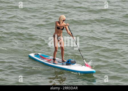 Southend on Sea, Essex, Regno Unito. 6 settembre 2023. Una giornata calda dell'attuale ondata di caldo ha attirato i visitatori nella città costiera di Southend on Sea, con alcuni che portano alle spiagge e all'acqua fresca dell'estuario del Tamigi. Paddle boarder femminile con bikini Foto Stock