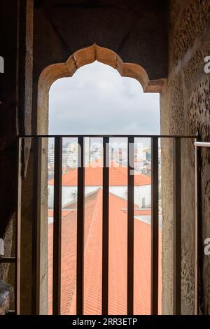 Porto, Portogallo, Chiesa di Clerigos e Torre. Paesaggio urbano e tetto del tempio cattolico visto da una finestra nel campanile o campanile. Muro di pietra o Foto Stock