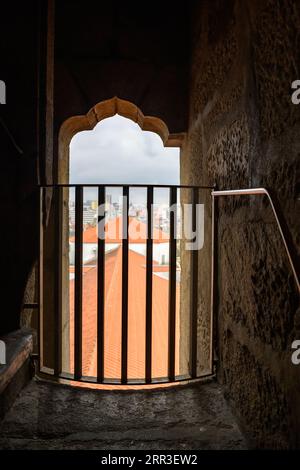 Porto, Portogallo, Chiesa di Clerigos e Torre. Paesaggio urbano e tetto del tempio cattolico visto da una finestra nel campanile o campanile. Muro di pietra o Foto Stock