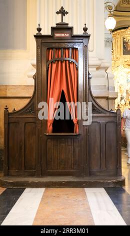 Saragossa, Spagna - 14 agosto 2023: Vecchio confessionale in legno con cortina rossa nella Cattedrale-Basilica di nostra Signora del pilastro Foto Stock