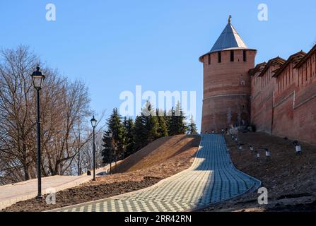 Una strada asfaltata e una lanterna vicino alle mura e alle torri dell'antico Cremlino a Nizhny Novgorod Foto Stock