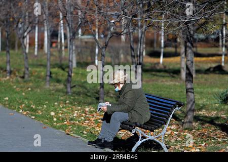 201127 -- BUCAREST, 27 novembre 2020 -- Una donna che indossa una maschera si siede sulla panchina in un parco nel centro di Bucarest, Romania, 27 novembre 2020. Le autorità rumene hanno imposto un coprifuoco di un mese in tutto il paese a partire dal 9 novembre. I residenti non possono lasciare le loro case dalle 23:00 alle 5:00, senza particolari circostanze. Foto di /Xinhua ROMANIA-BUCAREST-COVID-19-DAILY LIFE CristianxCristel PUBLICATIONxNOTxINxCHN Foto Stock