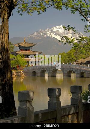 Piscina del Drago Nero di Lijiang con padiglione avvolgente e Ponte della cintura con la montagna di neve del Drago di Giada sullo sfondo Foto Stock