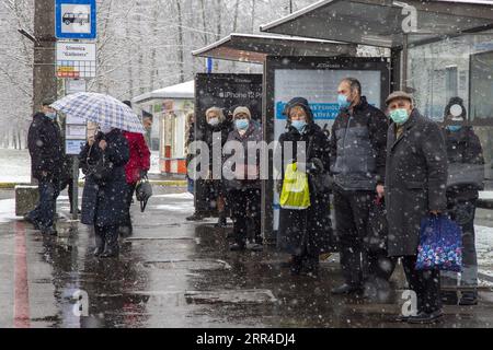 201130 -- RIGA, 30 novembre 2020 -- le persone che indossano maschere per il viso aspettano gli autobus sulla neve a riga, Lettonia, il 30 novembre 2020. Foto di /Xinhua LETTONIA-RIGA-SNOW EdijsxPalens PUBLICATIONxNOTxINxCHN Foto Stock