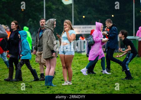 Due adolescenti adolescenti sotto pioggia e fango. Green Man Festival, Brecon, Galles, Regno Unito, 2023. Foto: Rob Watkins Foto Stock