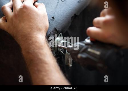 avvitatore a batteria che avvolge una vite in un foro di un divano da vicino Foto Stock