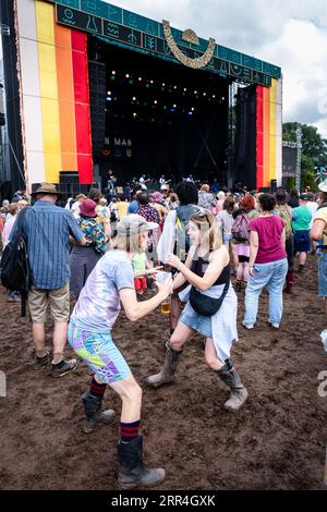 Una giovane coppia che danza con le birre nel fango al Mountain Stage al Green Man Festival, Brecon, Galles, Regno Unito, 2023. Foto: Rob Watkins Foto Stock