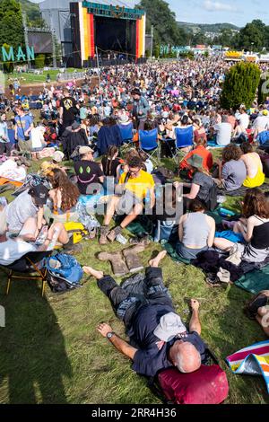 Un anziano di mezza età fa un pisolino al sole e mette i suoi pozzi fangosi sull'erba al Green Man Festival di Brecon, Galles, Regno Unito, 2023. Foto: Rob Wat Foto Stock