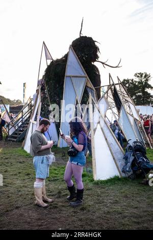 Una coppia che scorre sui loro telefoni cellulari al Wicker Man at Green Man Festival, Brecon, Galles, Regno Unito, 2023. Foto: Rob Watkins Foto Stock