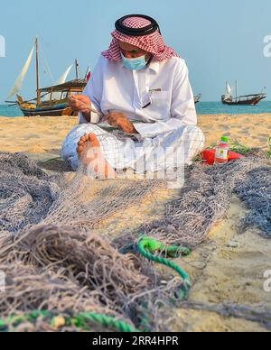 201205 -- DOHA, 5 dicembre 2020 -- Un pescatore ripara le reti da pesca sulla spiaggia di Katara durante il 10° Katara Traditional Dhow Festival a Doha, capitale del Qatar, 5 dicembre 2020. Il festival si è tenuto dal 1 al 5 dicembre qui per mettere in mostra le tradizioni marittime. Foto di /Xinhua QATAR-DOHA-TRADITIONAL DHOW FESTIVAL Nikku PUBLICATIONxNOTxINxCHN Foto Stock