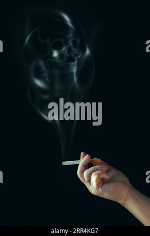 La mano umana tiene una sigaretta. Fumo a forma di cranio. Fumare uccide. Isolato su nero. Foto Stock