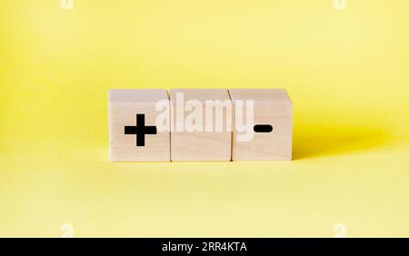 blocchi su sfondo giallo con un segno più e un segno meno. Concetto di scelta Foto Stock