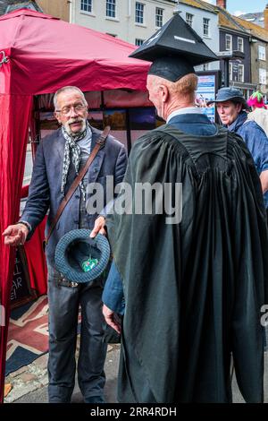 Bridport, Dorset. Inghilterra. Le persone celebrano il Bridport Hat Festival con copricapi fantasiosi e colorati. Un costume da preside e un cappello. Divertente. Foto Stock