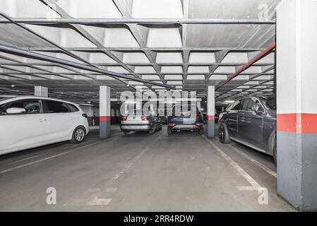 Auto parcheggiate e spazi vuoti in un garage sotterraneo Foto Stock