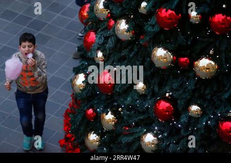 201214 -- PECHINO, 14 dicembre 2020 -- Un ragazzo cammina accanto a un albero di Natale nel centro di Beirut, Libano, 13 dicembre 2020. XINHUA FOTO DEL GIORNO BilalxJawich PUBLICATIONxNOTxINxCHN Foto Stock