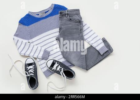 Maglione, jeans e scarpe eleganti per bambini su sfondo bianco Foto Stock