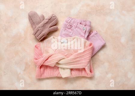 Maglione, pantaloni e guanti per bambini lavorati a maglia su sfondo colorato Foto Stock