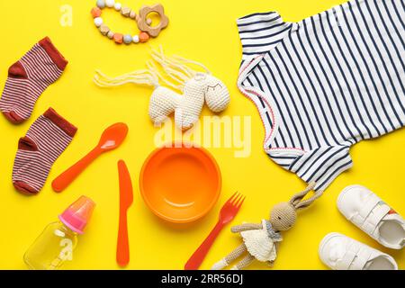 Composizione con diversi accessori e abiti per bambini su sfondo giallo Foto Stock