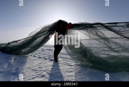 201227 -- FUHAI, 27 dicembre 2020 -- Un pescatore trasporta la rete per la pesca sul lago congelato Ulunggur nella contea di Fuhai, regione autonoma di Xinjiang Uygur della Cina nord-occidentale, 27 dicembre 2020. Ogni anno, i pescatori seguono il tradizionale metodo di pesca invernale mettendo sotto il ghiaccio una rete gigante per pescare sul lago Frozon Ulunggur, uno dei dieci laghi d'acqua dolce più grandi della Cina. CHINA-XINJIANG-FUHAI-ULUNGGUR LAGO-PESCA INVERNALE CN SADAT PUBLICATIONXNOTXINXCHN Foto Stock